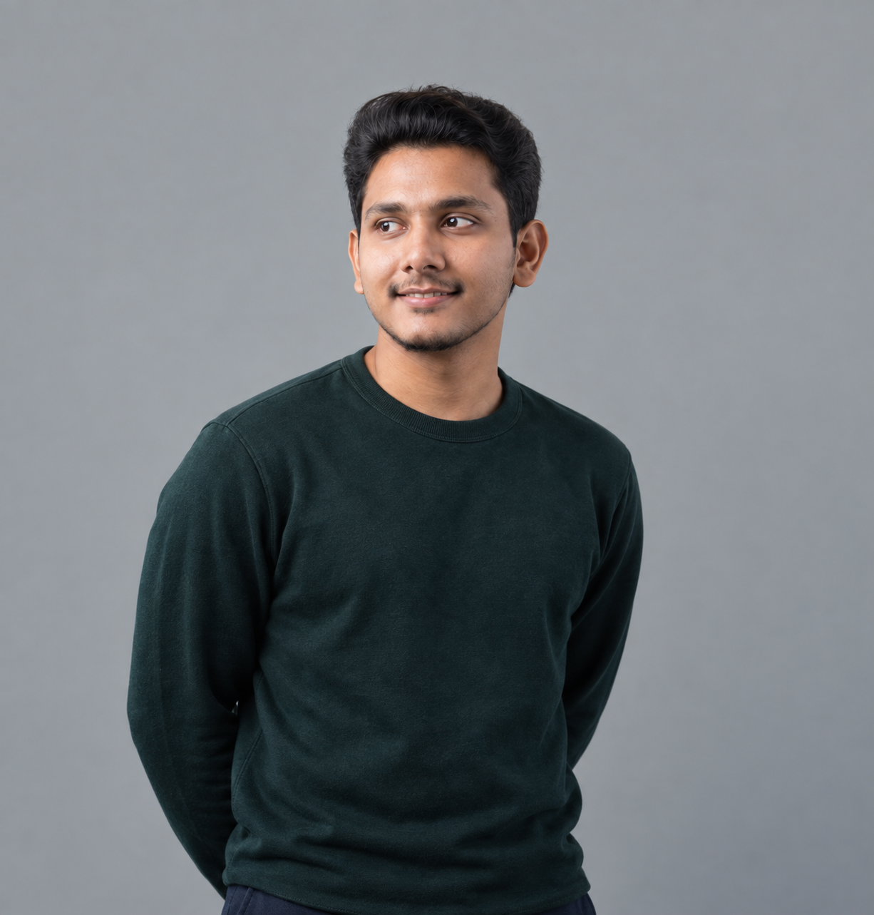 Bhanu Teja in a dark green crewneck, smiling and looking to the side